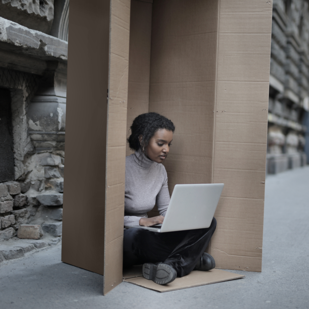 Woman writing on a laptop outside in a box