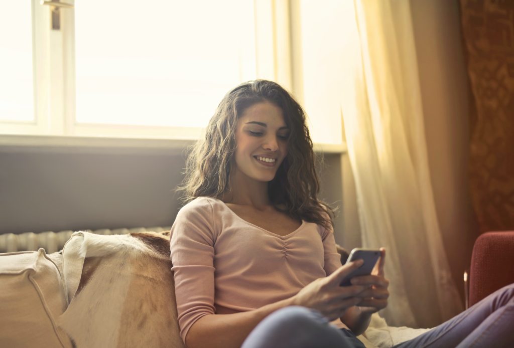 woman sat smiling at her phone