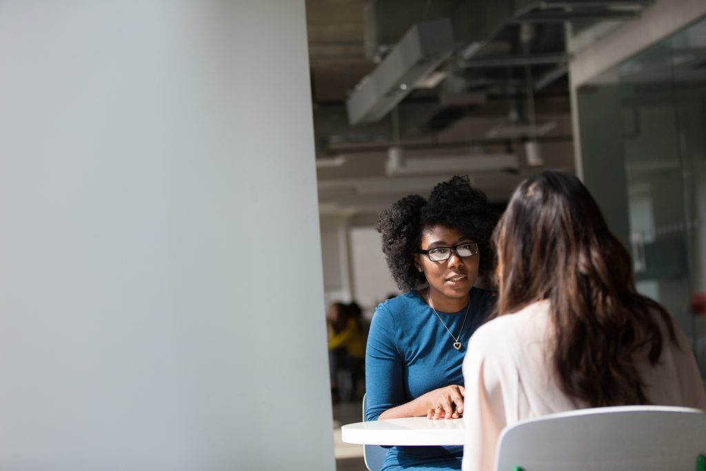 two women sat talking at work office