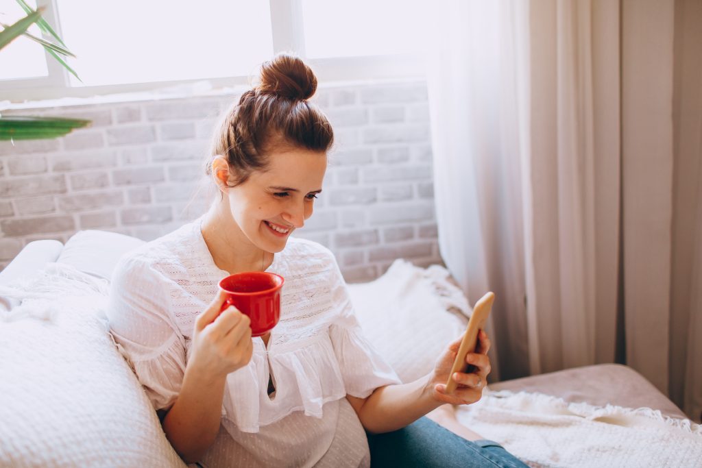 woman laughing at phone with coffee