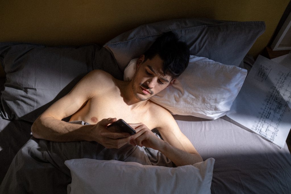 man lying in bed looking at phone