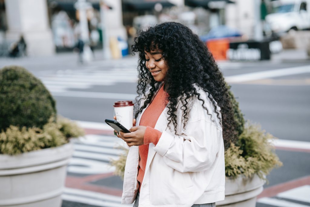 smiling woman looking at her phone with coffee